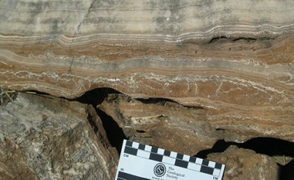 field photograph of massive flowstone layers from one of the South African hominin caves, with red cave sediments underneath. Photo credit: Dr Robyn Pickering 